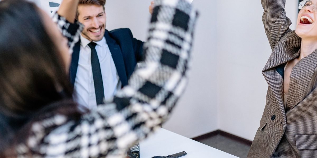Happy employees interacting positively in an office environment, reflecting the high engagement and strong bonds of a cohesive team.